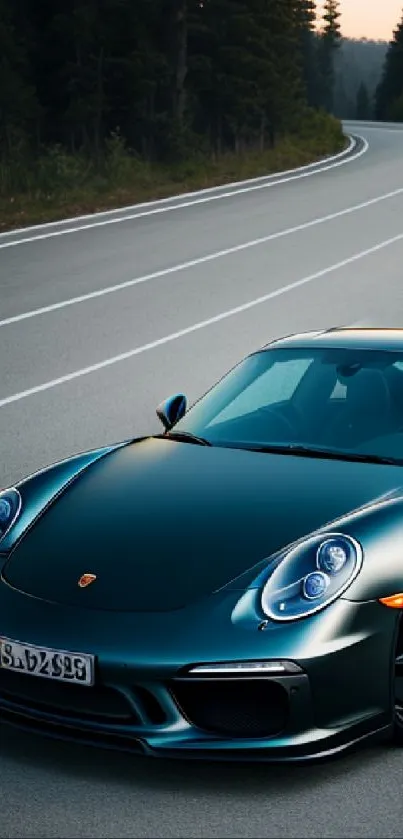 Sleek dark green sport car on a winding forest road at dusk.