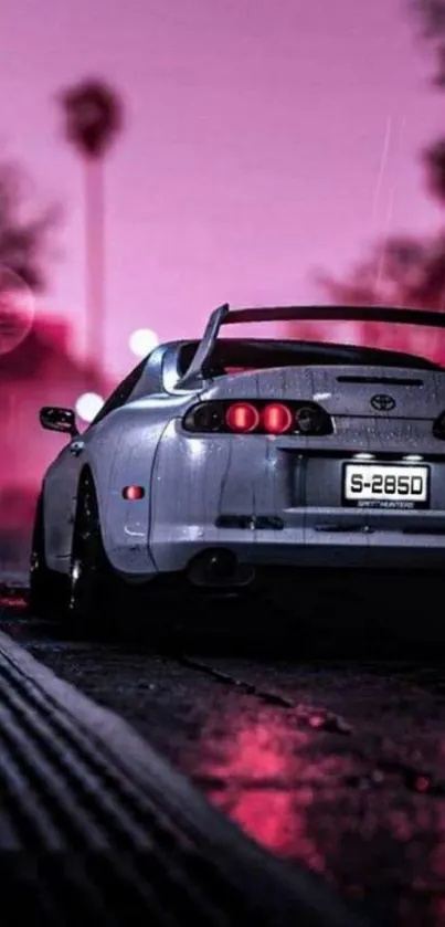 Sleek car under neon pink skies at dusk on a street.