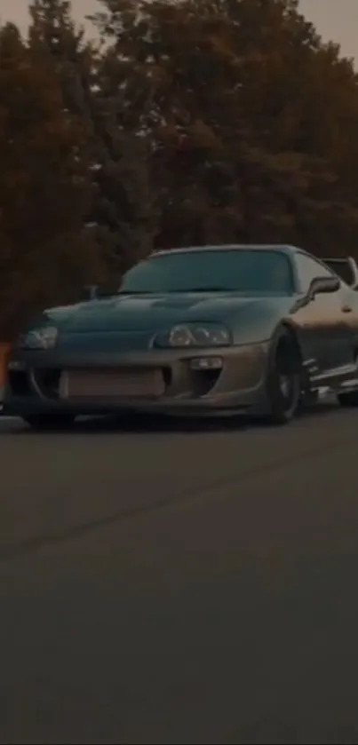 A sleek sports car speeding down a tree-lined road at dusk.