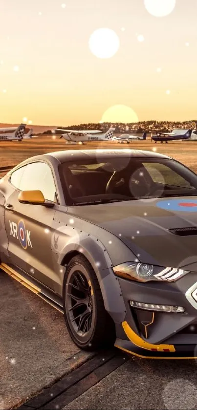 Grey sports car parked at sunset near airplanes.