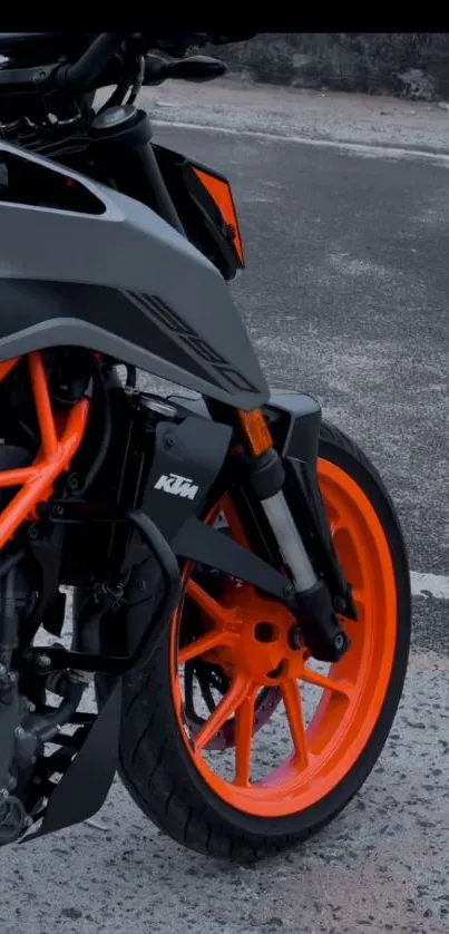 Vibrant orange motorcycle wheel on an asphalt road.