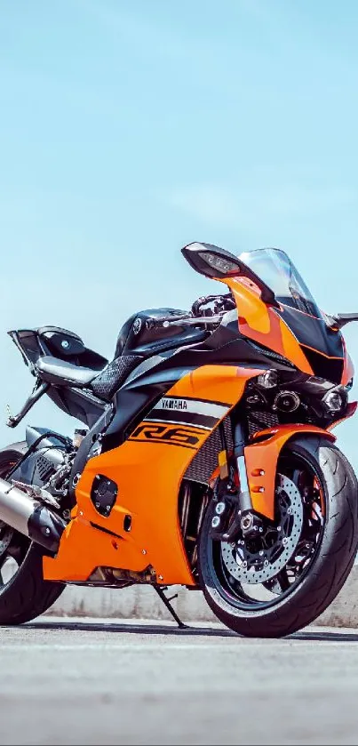 Orange motorcycle parked on a street with a clear blue sky backdrop.