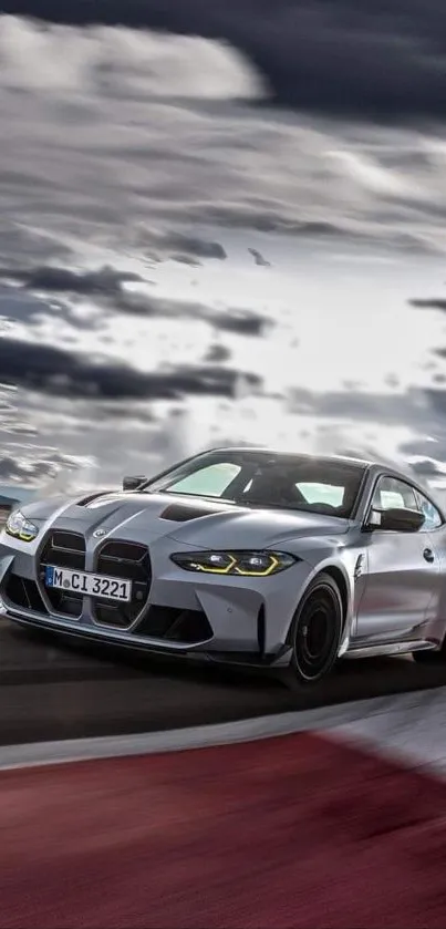 Sleek silver sports car racing under a dramatic sky on a track.