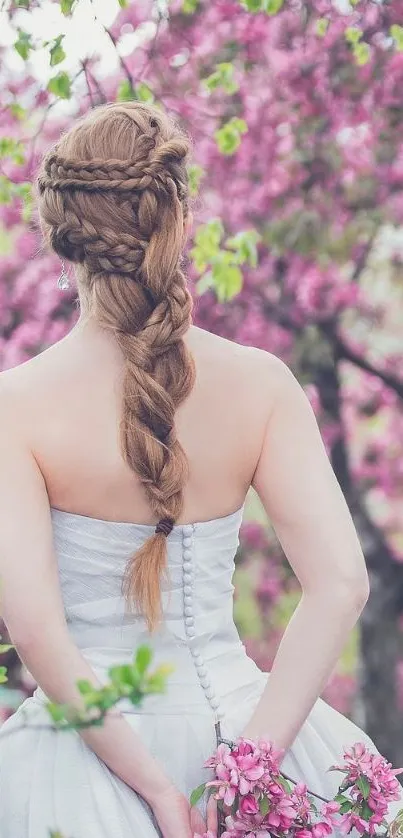 Woman in white dress with braided hair among pink blossoms.