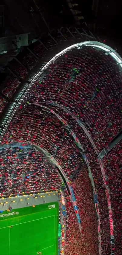 Aerial view of a crowded stadium at night with vibrant red seats.