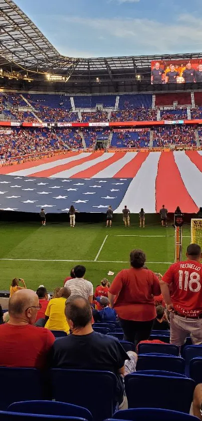 Stadium with large American flag display and spectators.