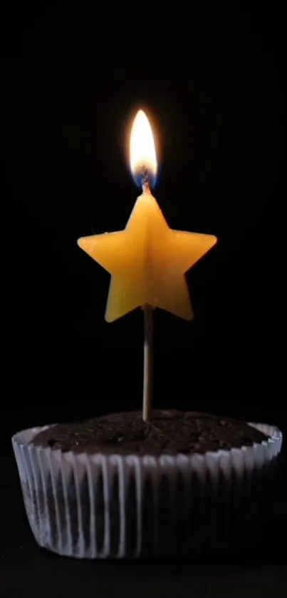 Star-shaped candle glowing on chocolate cupcake.