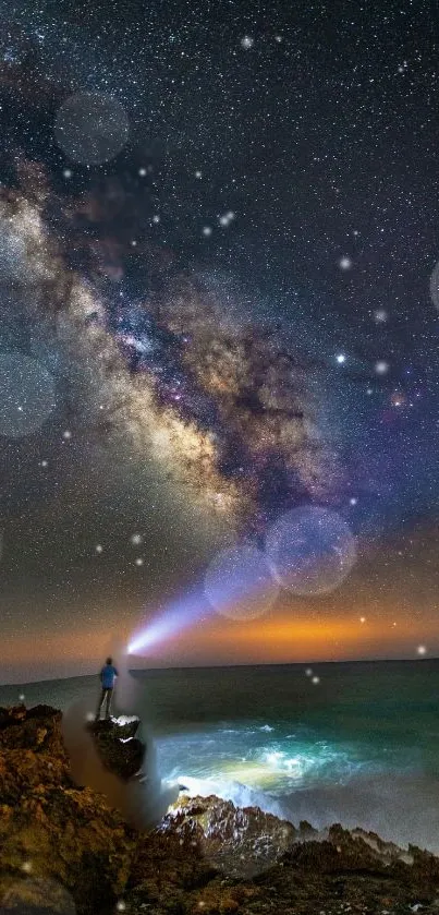 Person stands on rocks under the Milky Way and starry sky by the seaside.