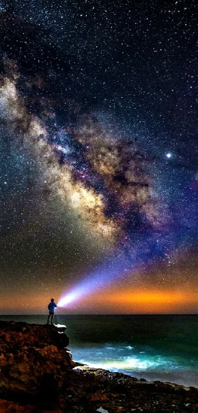 Stunning night sky wallpaper with galaxy view and stargazer on a rocky shore.