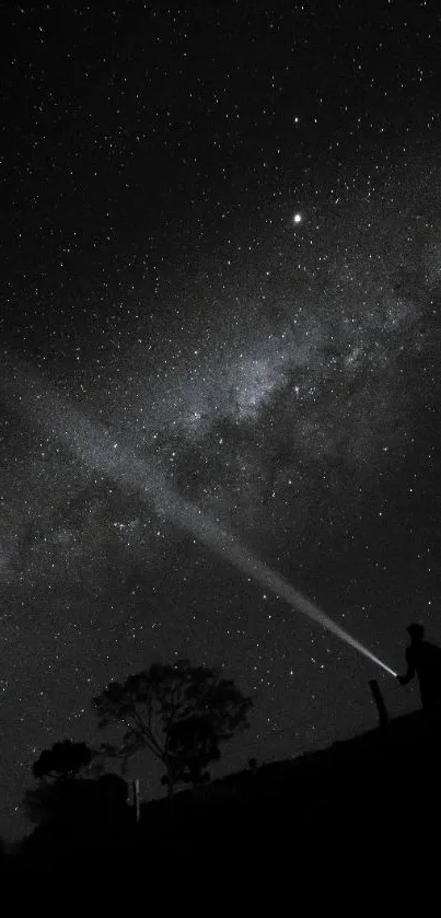 Silhouette stargazer under a starry sky with beam of light.