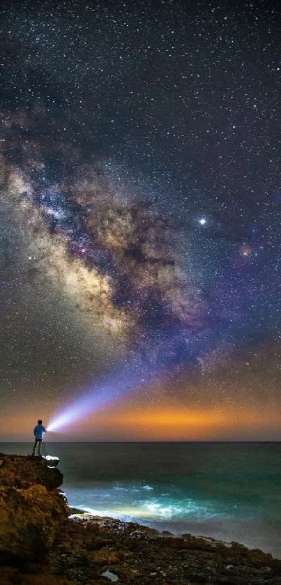 Person with flashlight admiring Milky Way under starry sky on a cliff.