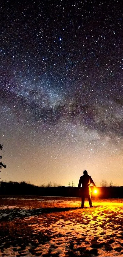 Silhouette under a starry night sky with glowing lantern.