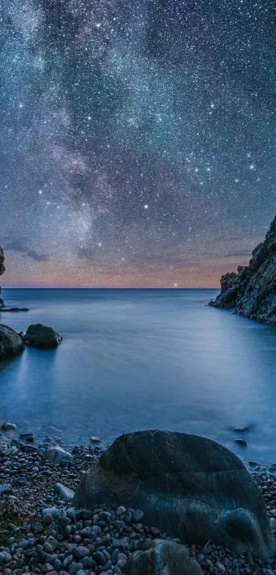 Starry night sky over a calm beach with rocky shoreline.