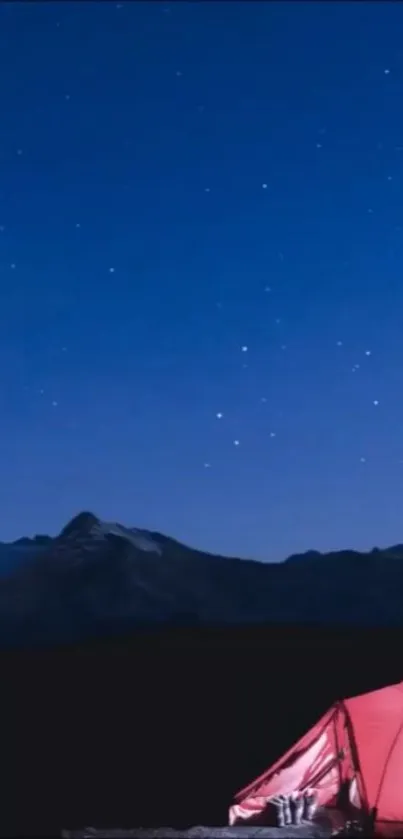 Red tent under starry night sky with mountains.