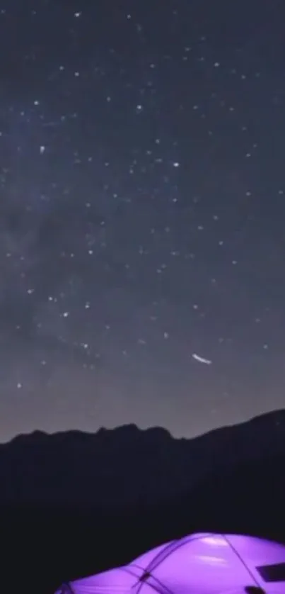 Tent glowing under a starry night sky with mountains in the backdrop.