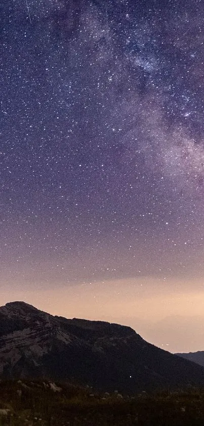 Starry night sky over mountains with a glowing tent on a mobile wallpaper.