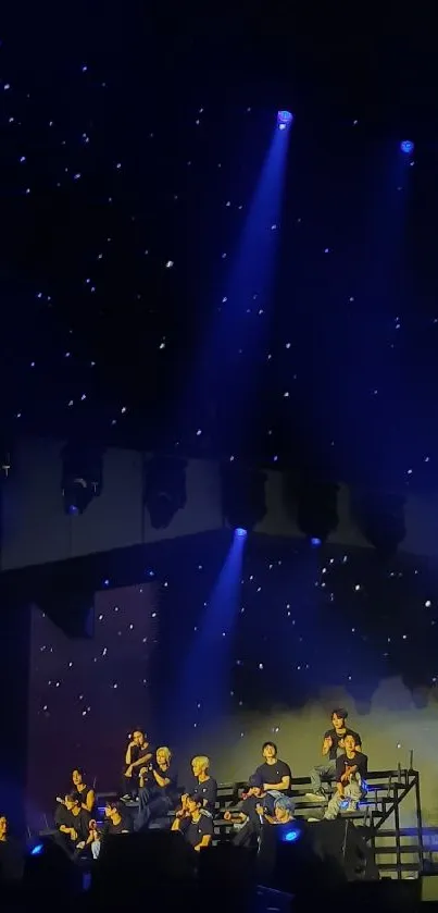 Concert stage illuminated by blue lights with a starry night sky background.