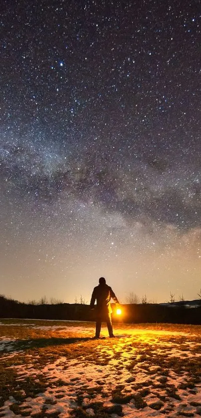 Silhouette under a starry night sky with lantern on a dark landscape.