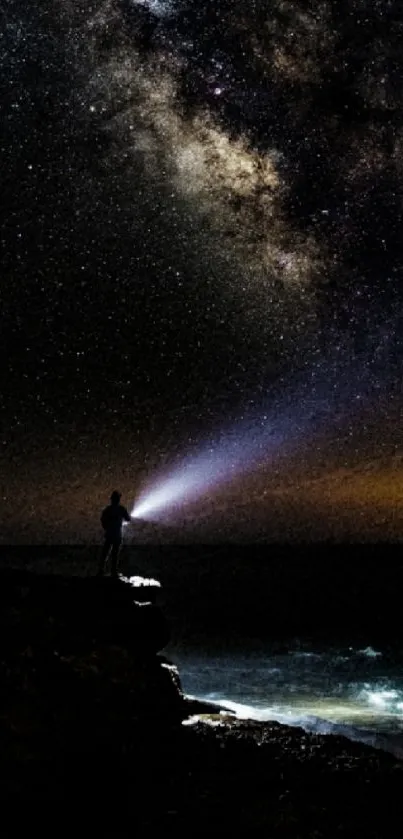 Person under starry Milky Way on cliff.