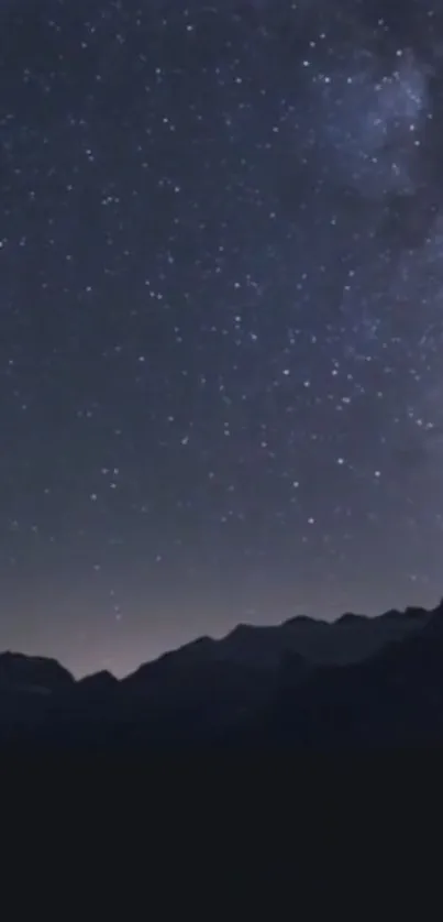 Beautiful starry sky over dark mountain silhouette.