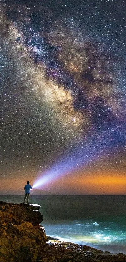 Person on cliff under a starry sky with the Milky Way over the ocean.