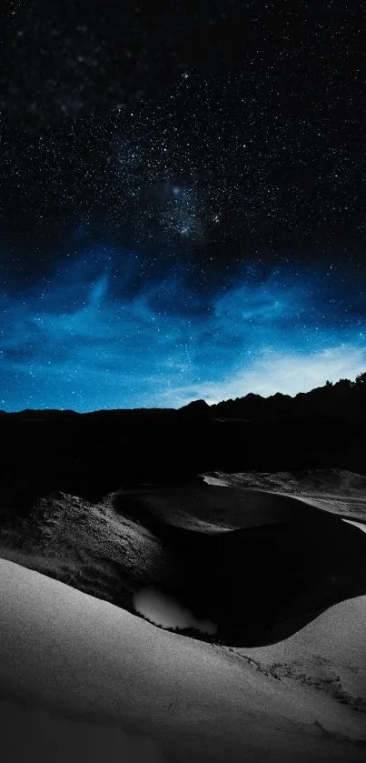 Starry sky over serene sand dunes at night.