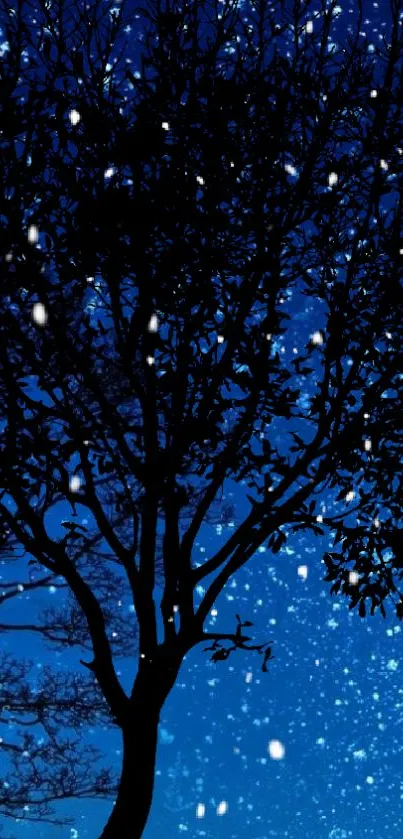 Silhouetted tree against starry blue night sky with falling snow.