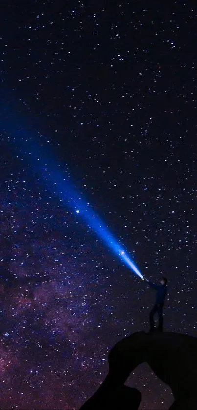 Silhouette on rock beneath the starry night sky and galaxy