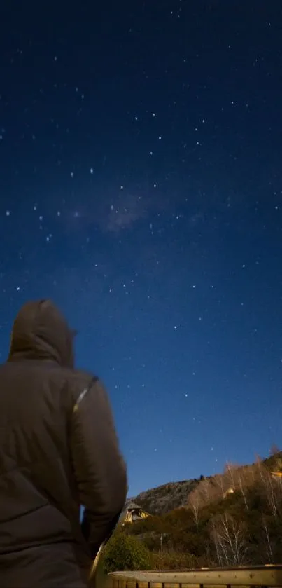 A person in a hoodie gazing at a starry night sky.