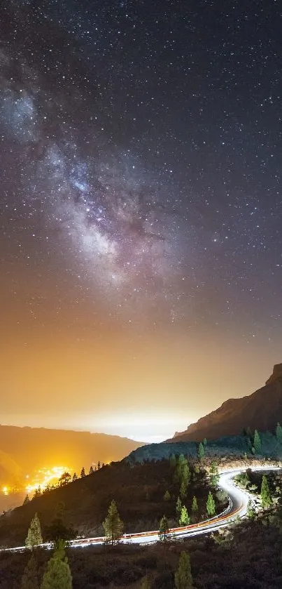 Starry night sky over mountains with city lights below.