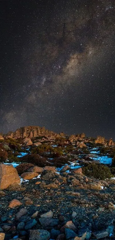 A breathtaking view of a starry night sky with Milky Way over rocky terrain.