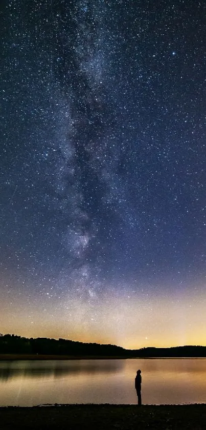 Silhouette by lake under starry night sky.