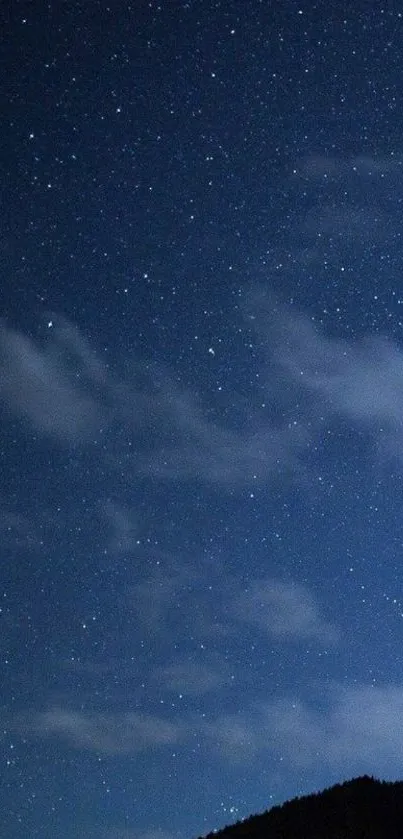 Breathtaking starry night sky with stars and clouds over a dark landscape.