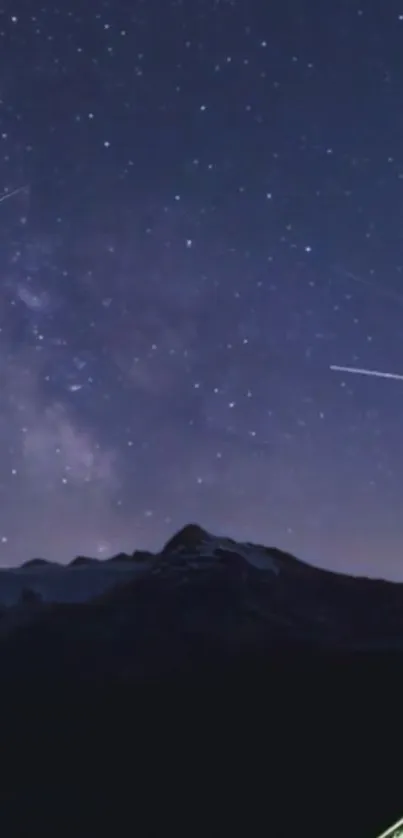 Starry night sky with shooting stars above mountains.