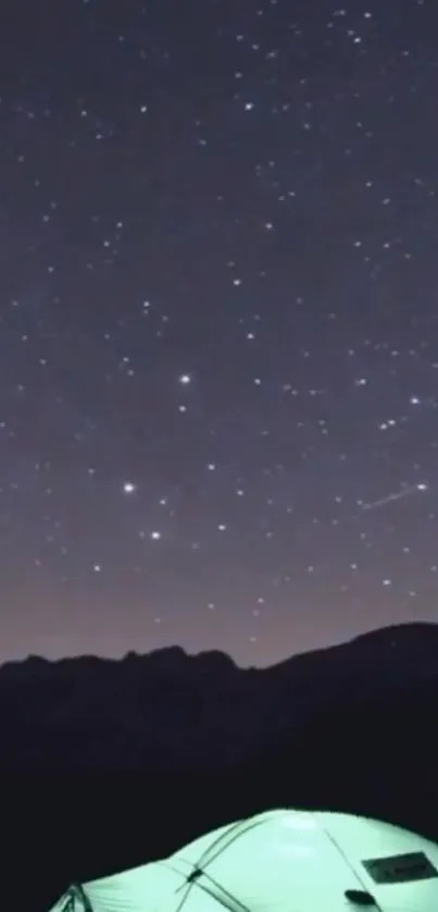 Glowing tent under a starry night sky with mountains.