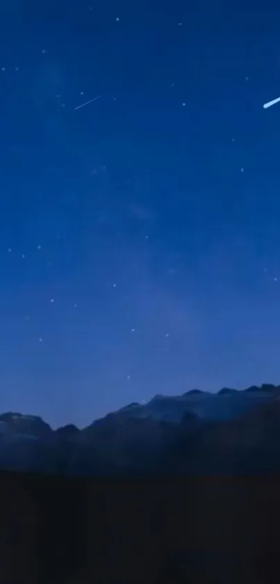 Starry night sky with mountains in silhouette.