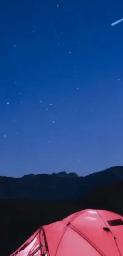 Starry night sky with red tent against mountain backdrop.