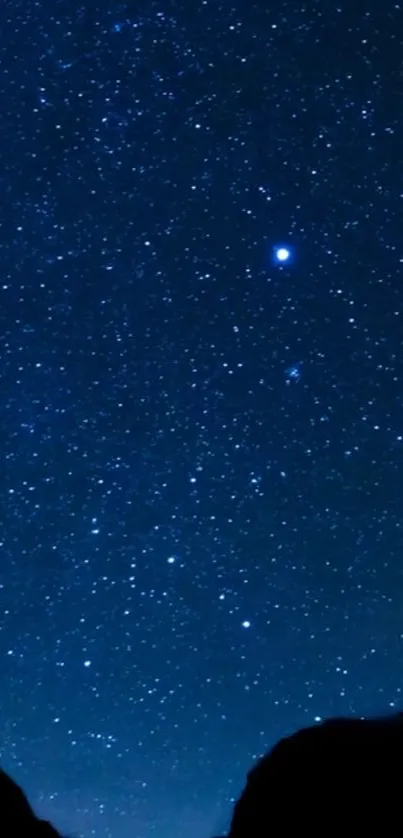 Starry night sky with silhouetted mountains.