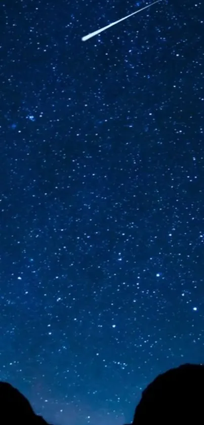 Starry night sky with shooting star over silhouette mountains.