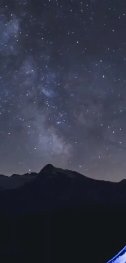 Starry night sky over mountains with a hint of blue tent light.