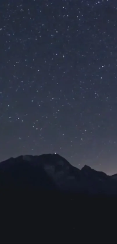 Starry night sky wallpaper with silhouettes of mountains.