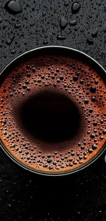 Steaming cup of coffee with rich foam texture on a dark background.