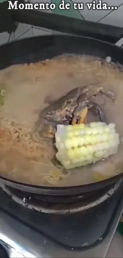 Steaming pot of noodle soup with corn and vegetables.