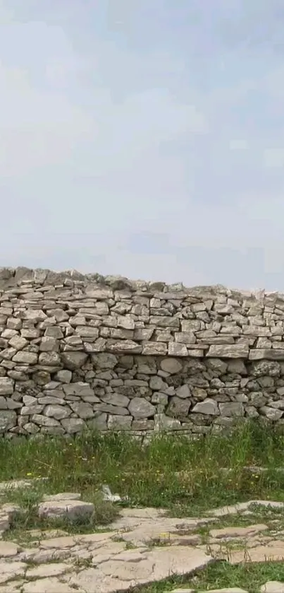 Stone wall landscape with grassy foreground under a cloudy sky.