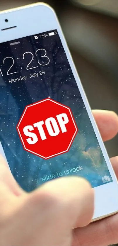 Close-up of a hand holding a phone with a red stop sign wallpaper.