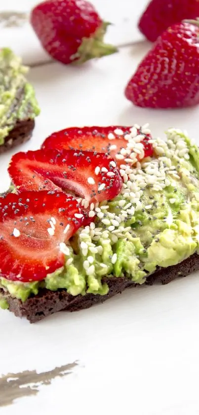 Close-up of strawberry and avocado toast topped with sesame seeds on a white surface.