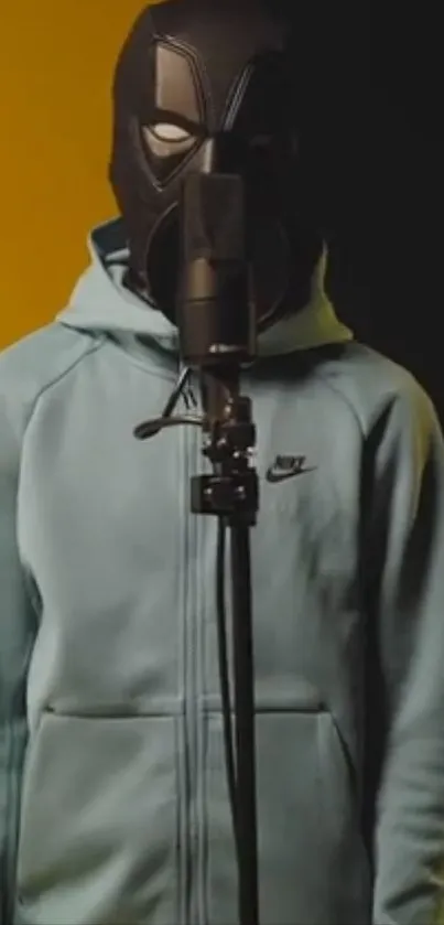 A masked artist in a hoodie stands in front of a microphone, with a dual-color backdrop.