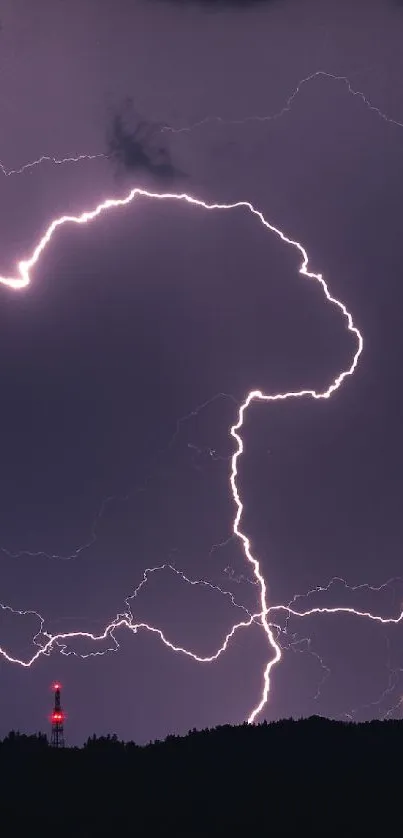 A dramatic lightning strike in a dark purple sky over a silhouette landscape.