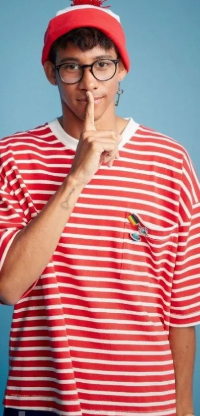 Person in red and white striped shirt with red beanie against blue background.