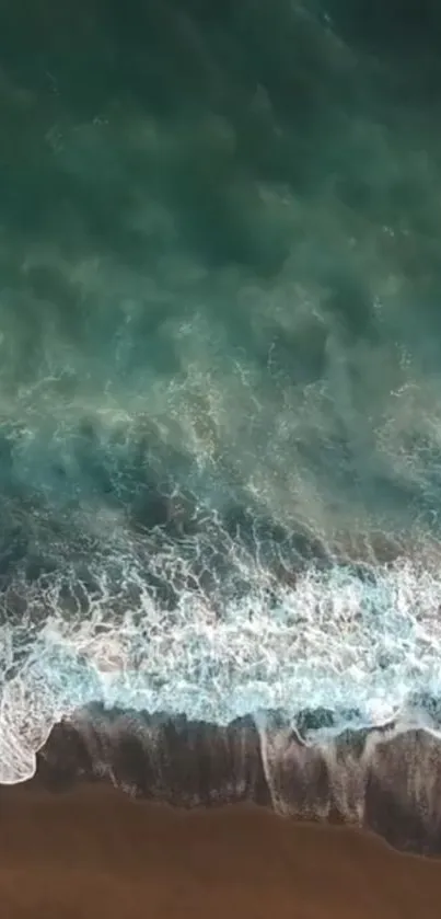 A breathtaking aerial view of ocean waves crashing on a sandy beach.